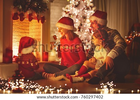 happy family father mother and children sitting by fireplace on Christmas Eve