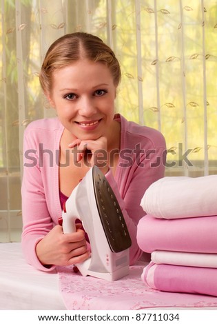 Happy young beautiful woman ironing clean clothes