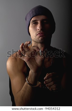 bad man with a cigarette offender in handcuffs on a gray background