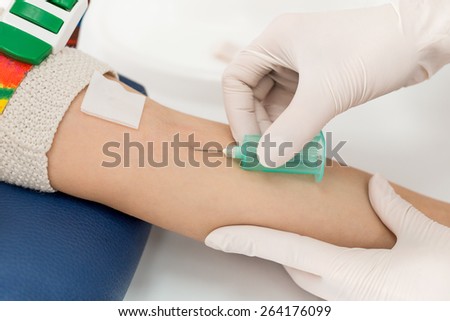 Close up preparation for blood test with pretty woman by female doctor in white coat medical uniform on the table in white bright room. Nurse pierces the patient\'s arm vein with needle blank tube.