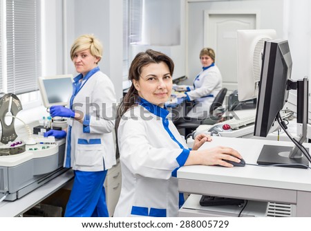 Medical workers women in white uniforms and gloves working in the laboratory of their computers in light and clean clinic. Nurses and beautiful and smiling.