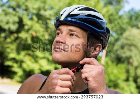 Serious professional cyclists wear a helmet for his safety and buttons on the helmet buckle under the neck. Bicycle helmet blue with white, in the morning in the green forest.
