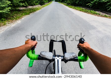 Riding on flat road asphalting in the forest. Hands on the steering wheel bicycle. Eye view from cyclist head