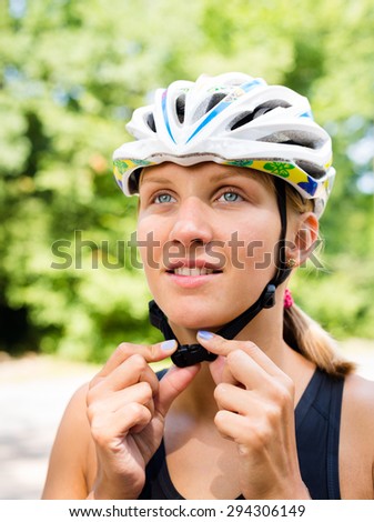 Serious professional cyclist girl wear a helmet for his safety and she is preparing to competition in cycling and triathlon. Bicycle helmet white, in the morning in the green forest.