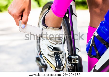 Professional cyclist triathlete buttons cycling shoes on the clasp to secure the foot on the pedal bike.