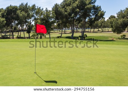 Red flag in the hole on a green golf field golf course