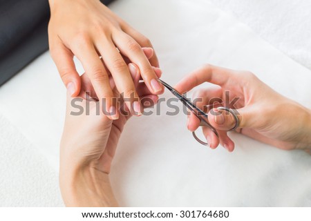 Lady having a manicure on her fingernails from a professional manicurist in a salon or spa, close up view from above of their hands