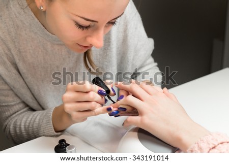 Process of doing manicure in the spa salon. Beautician applying black nail polish on the nails in the beauty salon. The concept of hand care.