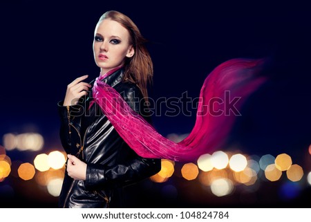 Young beautiful woman in leather jacket on background of night lights