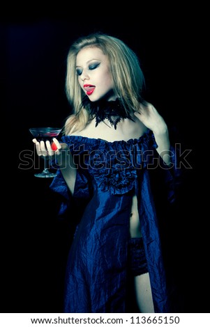 Aggressive vampire woman with glass of wine on black background