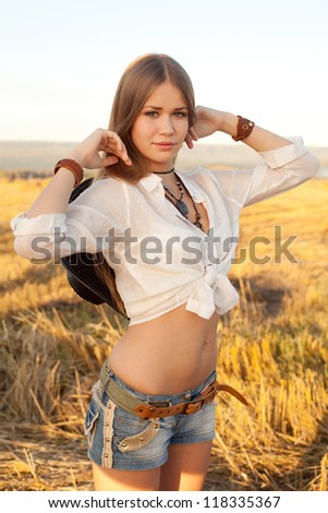 Portrait of woman at the field. Young woman in costume of cowboy looks at camera.