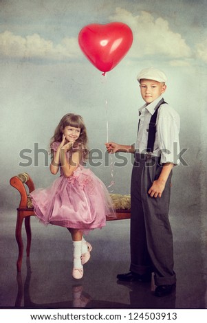 The boy gives a red balloon to the girl. Photo in retro style with old textured paper.