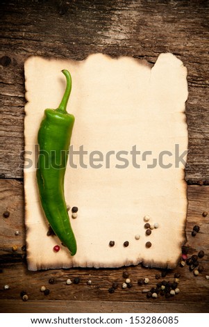 One Red Hot Chili Pepper with the Old Paper sheet on old wooden table