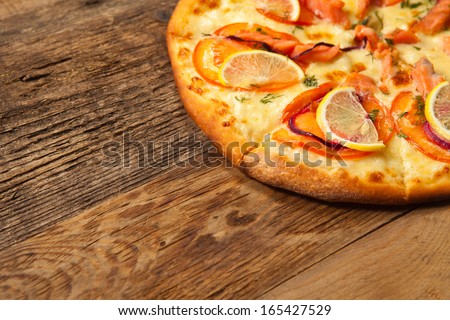 Salmone pizza on old wooden table. With place for text.