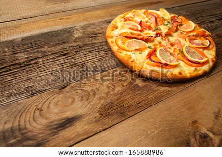 Salmone pizza on old wooden table. With place for text.
