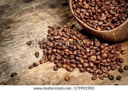 Wooden cup with coffee-beans on old wooden table