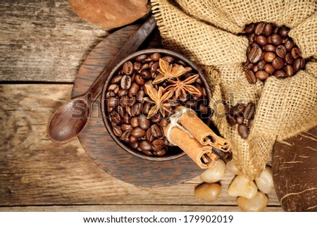 Wooden cup with coffee-beans and spicery on old wooden table. Top view.