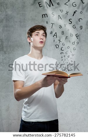 Young man holding a book with alphabet letters coming out of the book