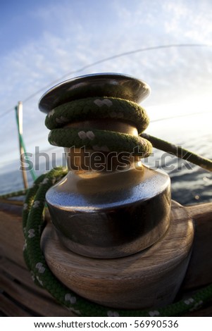 Large winch with line wrapped around and set sail in background