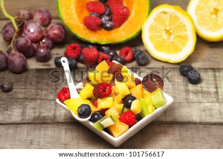 greedy fruit salad with red fruits and  fruits background on wood