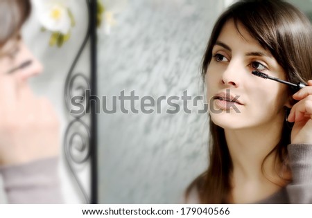 girl at mirror making up her eyes