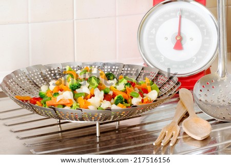 vegetable steamer with vegetables MIX INSIDE AND BALANCE OVER DRAINING BOARD