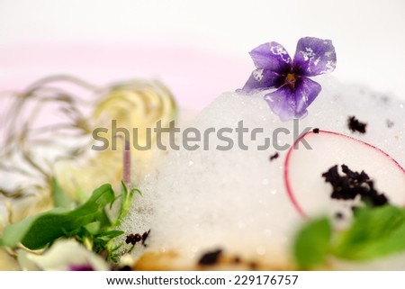 detail of creative serving dish with edible flowers, mint and artichoke,