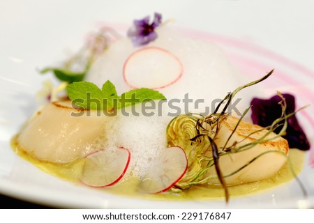 serving dish with scallops over artichoke cream and edible flowers