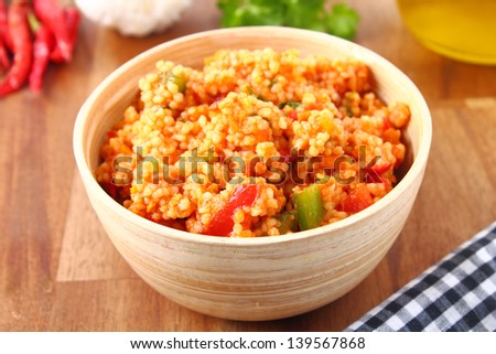 tabbouleh made of couscous and various vegetables. Served in a small bowl on a wooden board.