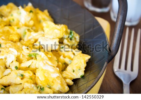 scrambled eggs with chives and herbs. Served in an iron pan.