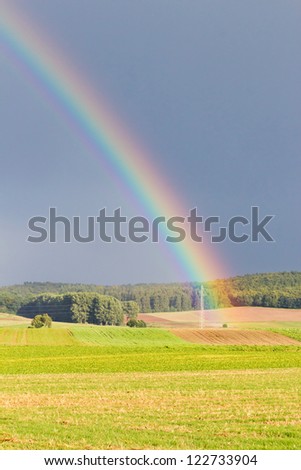 Detail of a bright rainbow in autumn in front of a dark overcast sky