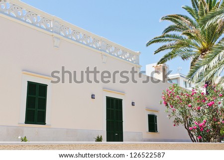 Detail of a spanish house with a white front and green shutters