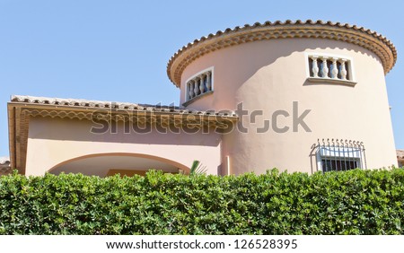 Typical spanish house behind a green hedge in front of a blue sky