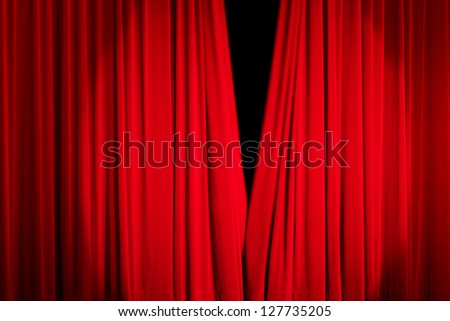 Red rising curtain with a light spot in a theater