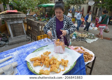 LUANG PRABANG, LAOS - MARCH 1: Woman sells fritters at the market on March 1, 2014 in Luang Prabang, Laos.
