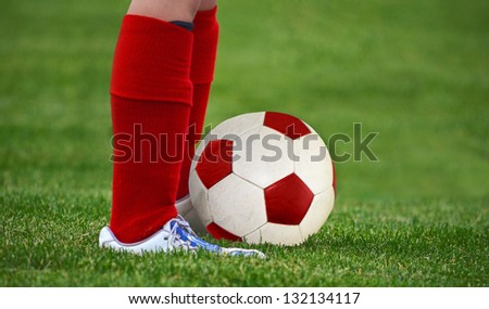 young soccer player with red knee socks and ball