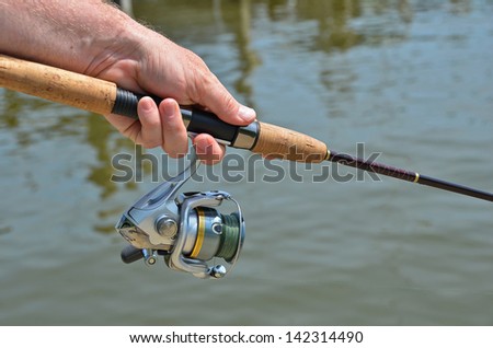 man\'s hand holding a fishing pole
