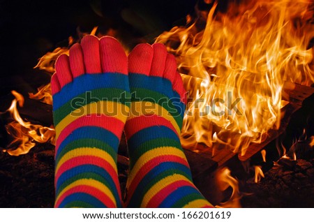 striped toe socks on feet warming by a fire