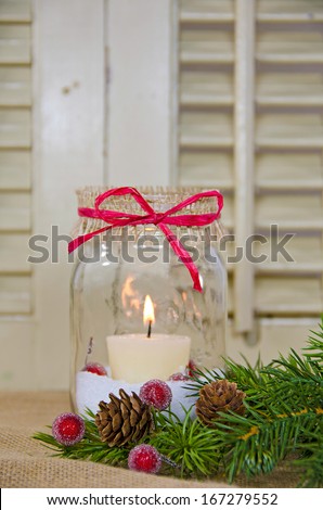 candle in Christmas mason jar with pine and berries