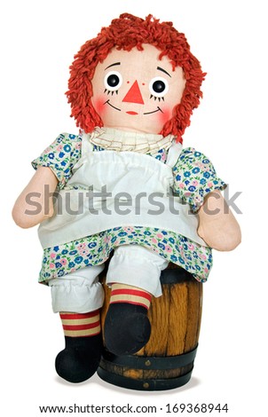 old rag doll sitting on a wooden barrel
