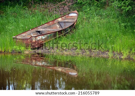 rusty row boat in pond water reflection