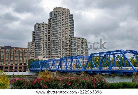blue bridge in Grand Rapids Michigan with tall building on an overcast day