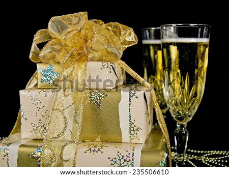 elegant Christmas gift with flutes of champagne and gold glittery bow on black
