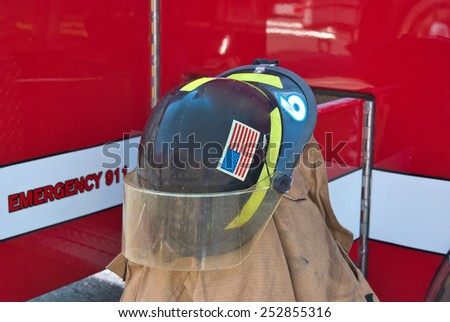 firefighter\'s helmet on coat by red fired truck