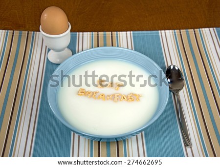 breakfast cereal in blue bowl on striped cloth with brown hard boiled egg
