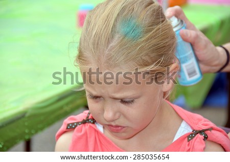 young Caucasian girl getting her blond hair spray painted