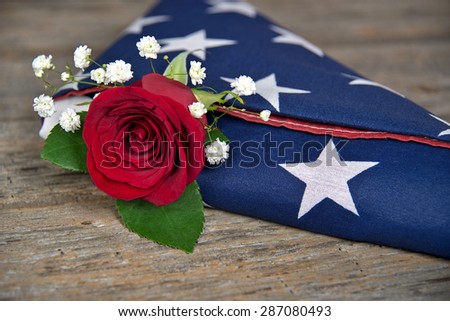 red rose tucked inside a folded American flag
