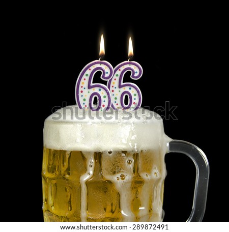 lit birthday candles for 66th birthday in a mug of beer isolated on black