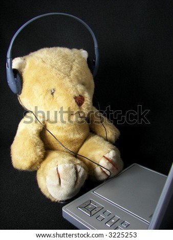 teddy bear with DVD player and headphone on black