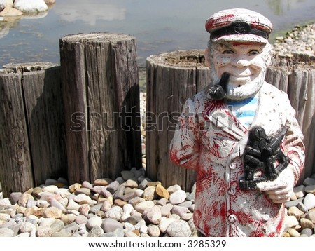 statue of old ship captain with weathered dock pilings and stones